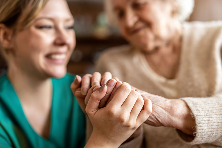 wings home care giver holding hands of hospice patient