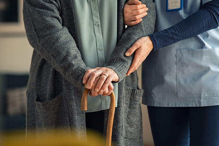 Elderly Person With Cane Being Cared For